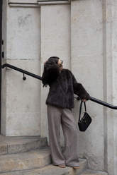 a lady in a black eco-friendly fur coat and a pair of grey pants
